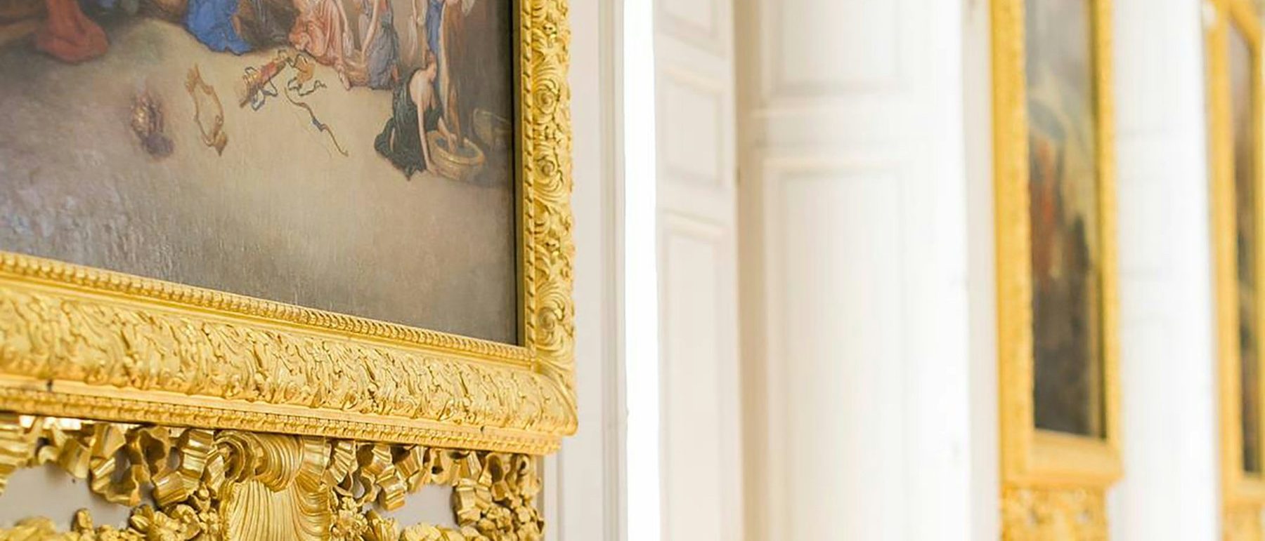 Gilt-framed paintings hung along a gallery wall